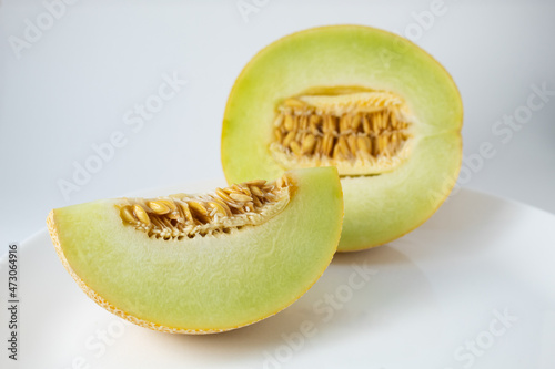 Ripe Gaul melon, cut in half with the seeds showing. Tropical fruit with white streaks on the yellow skin