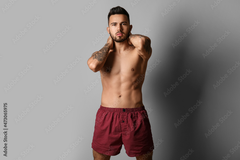 Handsome young man in underwear on grey background