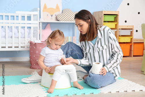 Mother potty training her little daughter at home