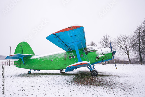 An old, abandoned plane in green and blue on a snowy winter day photo