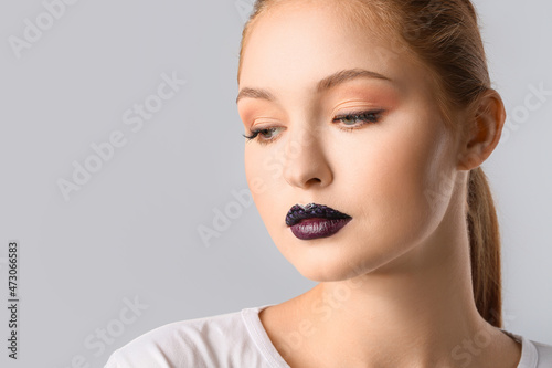 Beautiful young woman with unusual makeup on grey background