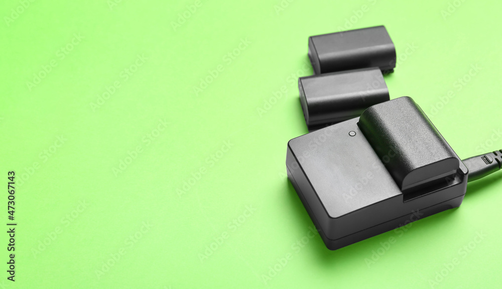 Camera batteries and charger on green background Camera batteries and charger on green background