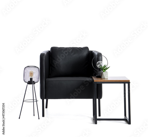 Black armchair with table, lamps and houseplant on white background