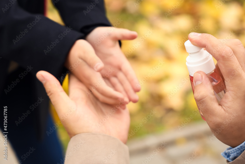 Man disinfecting hands of his little daughter before school, closeup Man disinfecting hands of his little daughter before school, closeup