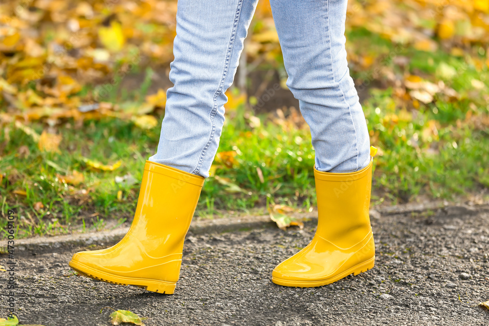 Woman in yellow gumboots walking in autumn park