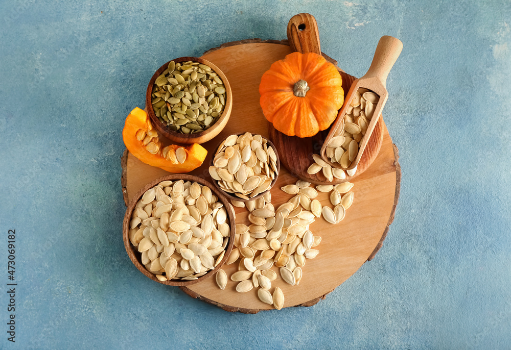 Fototapeta premium Bowls with natural pumpkin seeds on blue background