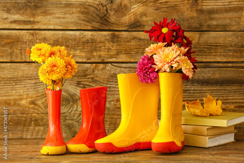 Rubber boots, flowers and books on wooden background