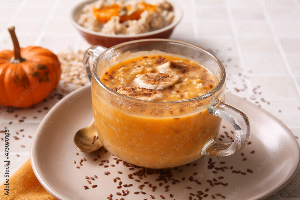 Pot of tasty oatmeal with pumpkin and banana on tile background Pot of tasty oatmeal with pumpkin and banana on tile background