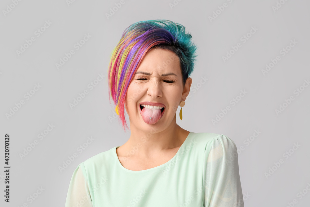 Grimacing woman with unusual hair on grey background Grimacing woman with unusual hair on grey background