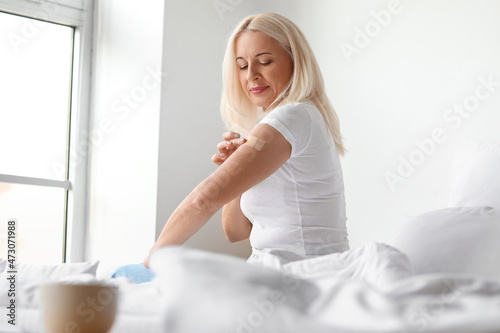 Mature woman applying nicotine patch at home. Smoking cessation