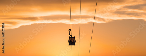 Silhouettes of people in the cabin of the aerial gondola road on a summer evening