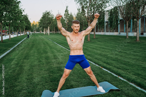 athletic man in blue shorts working out in the park