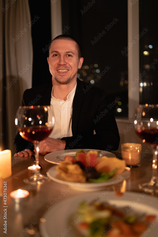 valentine's day dinner, portrait of a man at a festive table with red wine and candles, romantic home date, the guy prepared a surprise for girlfriend valentine's day dinner, portrait of a man at a festive table with red wine and candles, romantic home date, the guy prepared a surprise for girlfriend