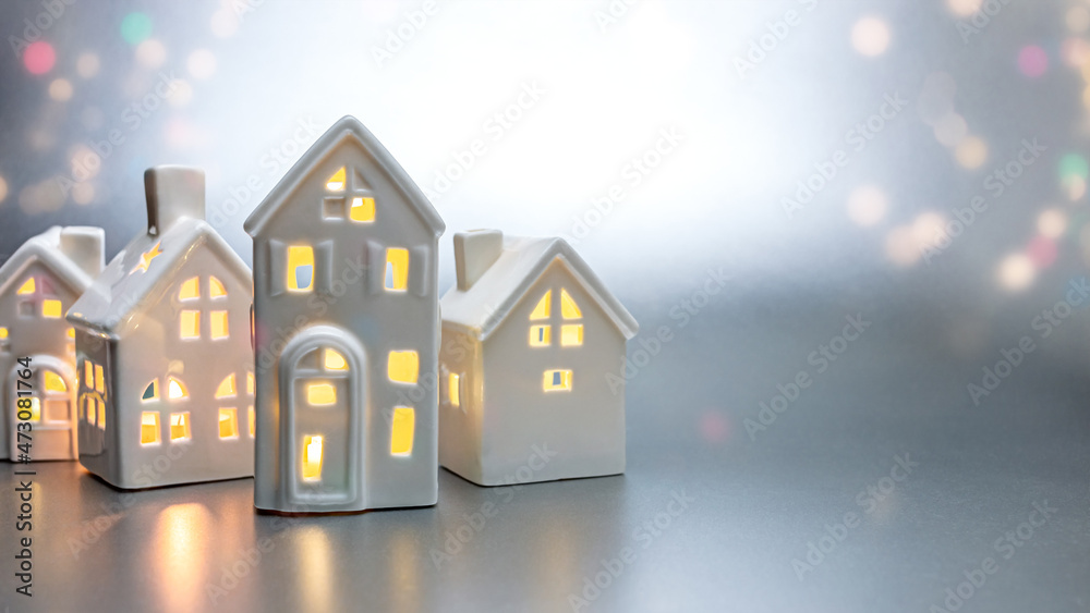 little toy white houses with burning lights inside. christmas decorations on abstract light background. little toy white houses with burning lights inside. christmas decorations on abstract light background.