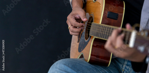 Close up shot of guitarist playing acoustic blues guitar on black background with copy space