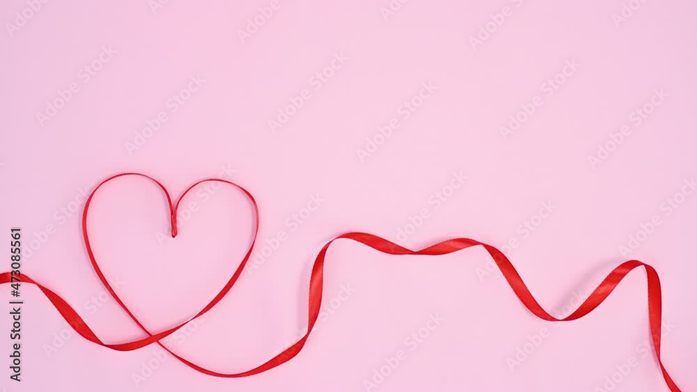 Red ribbon make Valentine's day heart on pastel pink theme. Stop motion