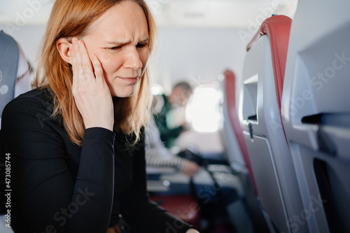 a woman on an airplane has a headache and an earache while flying on an airplane photo
