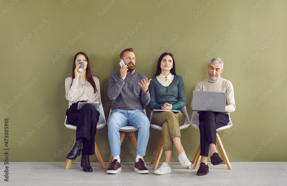 Group of different people waiting in line for business meeting or job interview, sitting on chairs by green wall in company hall or bank corridor, drinking coffee, using laptop or talking on phone Group of different people waiting in line for business meeting or job interview, sitting on chairs by green wall in company hall or bank corridor, drinking coffee, using laptop or talking on phone
