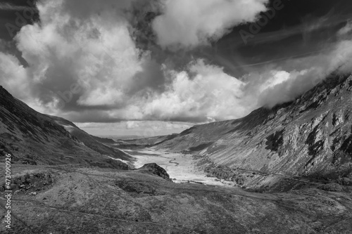 Black and white Aerial view of flying drone Epic landscape image in Autumn looking down Nant Fracon valley from Llyn Idwal with moody sky and copyspace