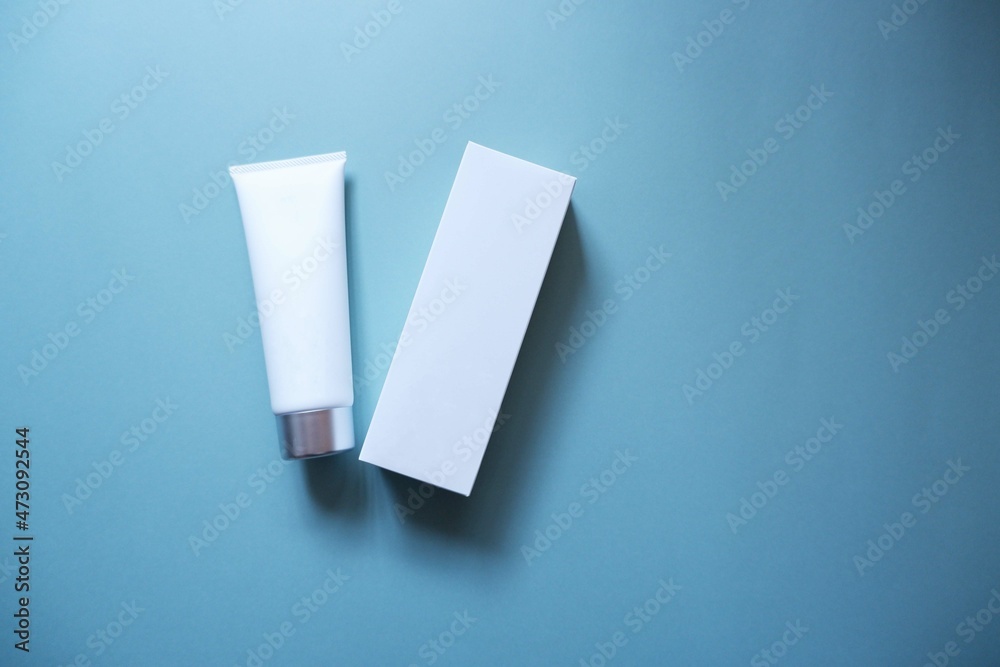 White squeeze bottle plastic tube and box on blue background. spa & cosmetics concept, flatlay, top view. Mockup, template. White squeeze bottle plastic tube and box on blue background. spa & cosmetics concept, flatlay, top view. Mockup, template.