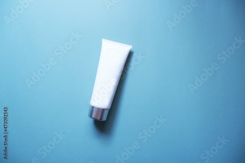 White squeeze bottle plastic tube on blue background. spa & cosmetics concept, flatlay, top view. Mockup, template. photo