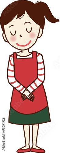 エプロンをして両手を前に合わせる女性。	