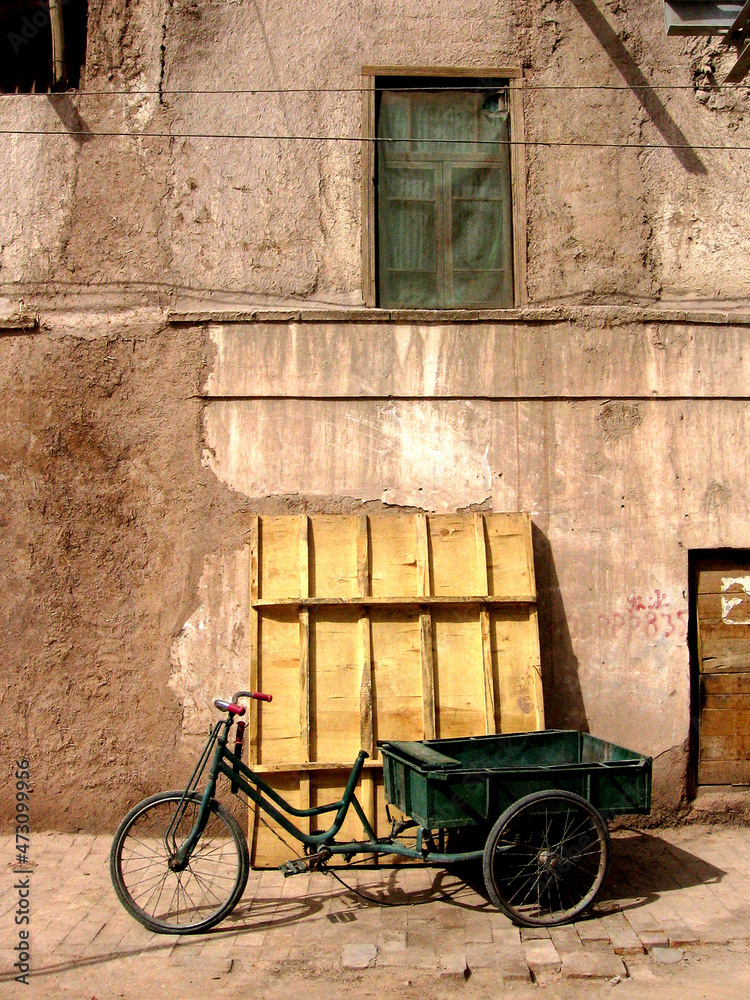 Bicycle pulling cart against an old building