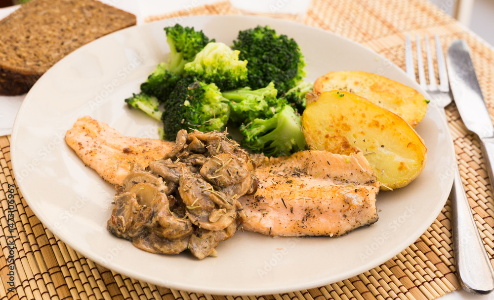 fried river trout fillet with a complex side dish of broccoli, baked potatoes and mushroom sauce fried river trout fillet with a complex side dish of broccoli, baked potatoes and mushroom sauce