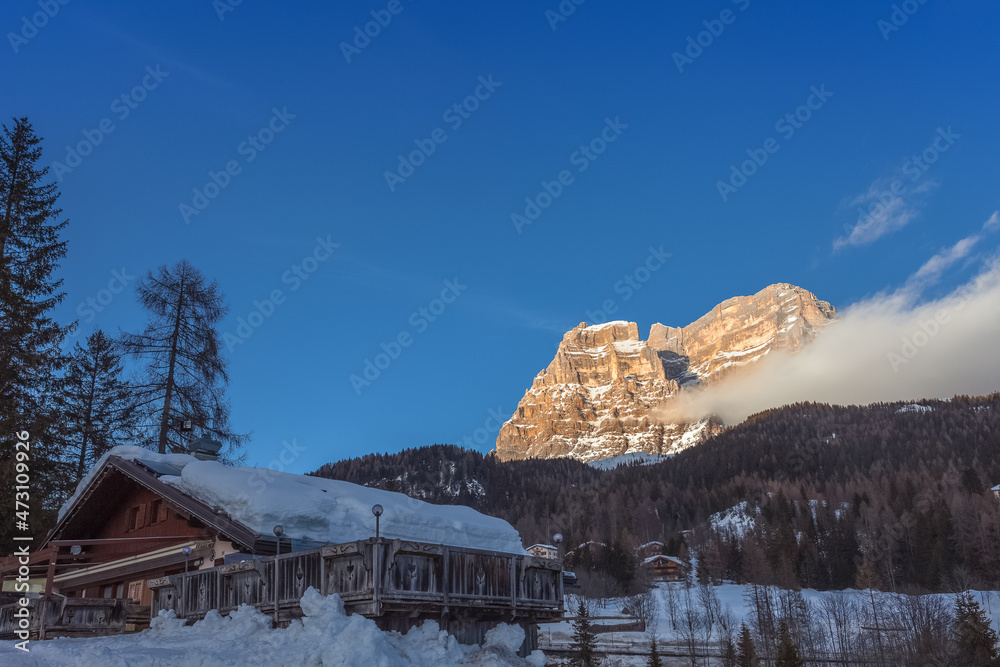 Snow-covered hut with Mount Pelmo in the background at sunset, Zoldo Valley, Dolomites, Italy