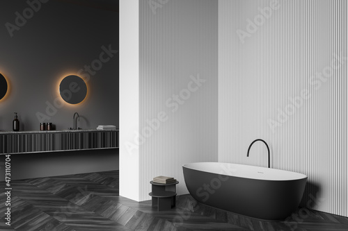 Dark bathroom interior with bathtub  sink and mirror  parquet floor