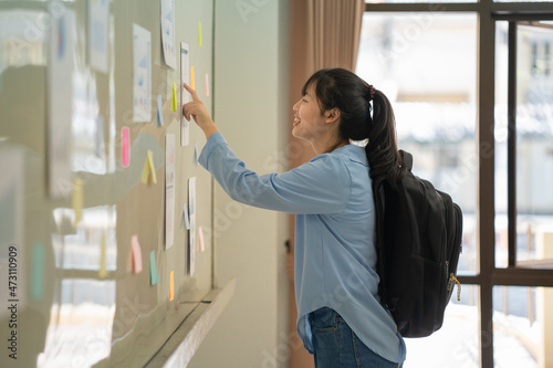 Canvas Print A female student looking at the notice posted on the board