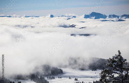 paysage alpin: Chamrousse et le massif de Belledonne sous la neige en hiver avec des nuages dans la vallée