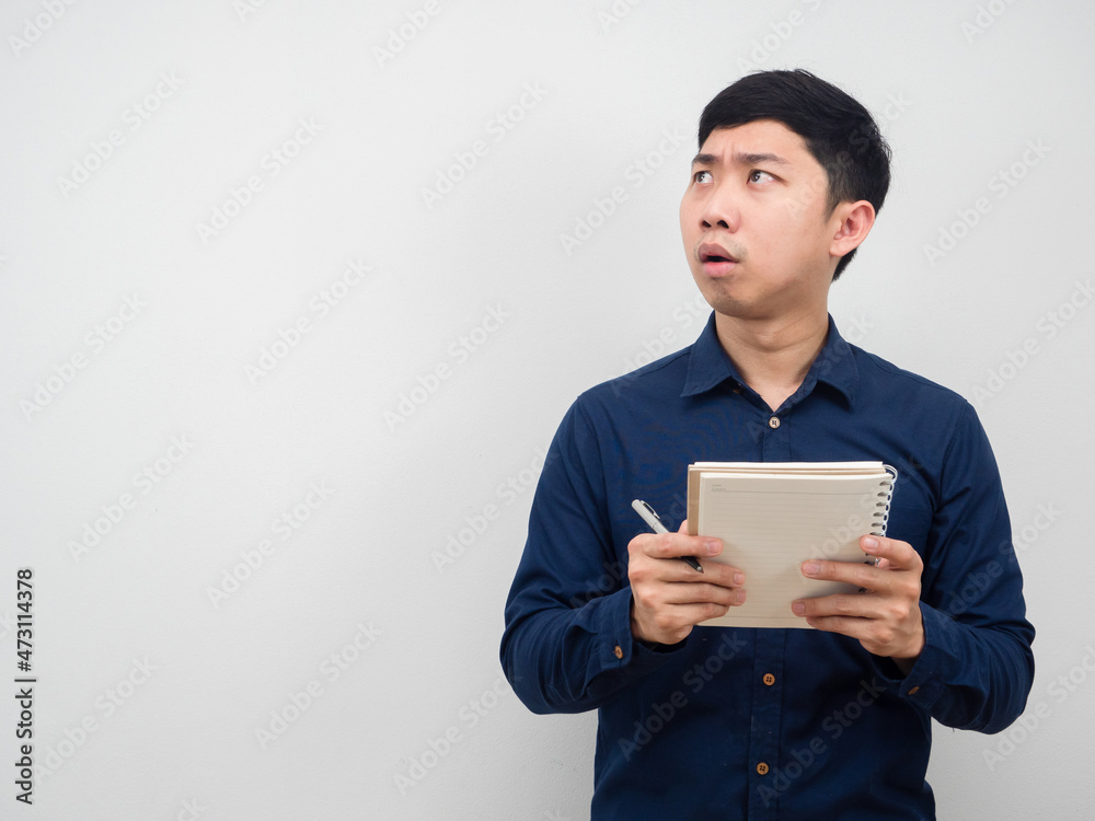 Asian man holding pen and diary feeling shocked looking at copy space Asian man holding pen and diary feeling shocked looking at copy space