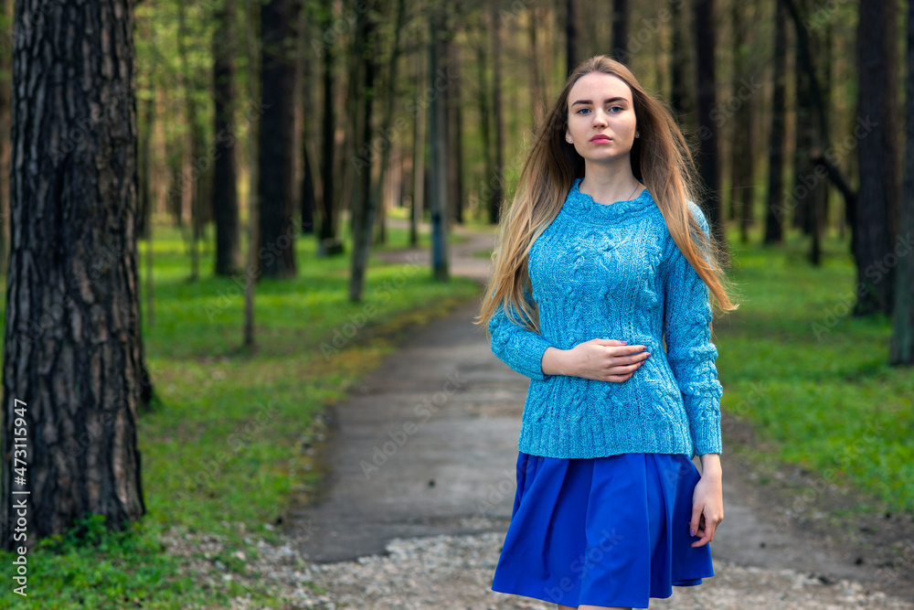Woman posing in spring forest in blue knitted sweater
Woman posing in spring forest in blue knitted sweater