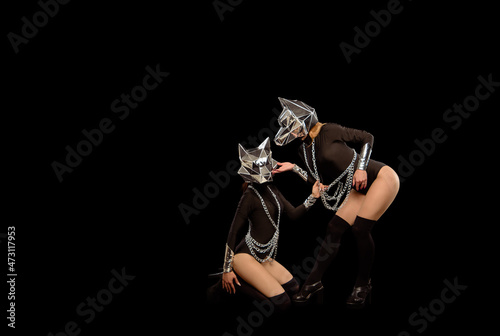 Fototapeta Naklejka Na Ścianę i Meble -  Two go-go variety show dancers in wolf masks on black