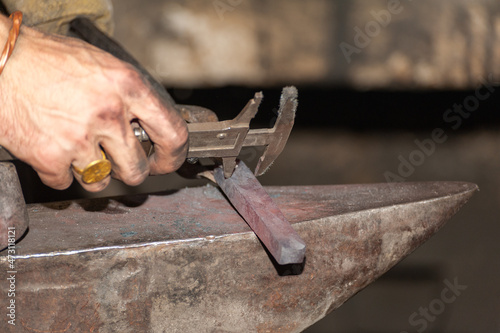 Detail shot of hammer forging hot iron at anvil © Pavlo Burdyak