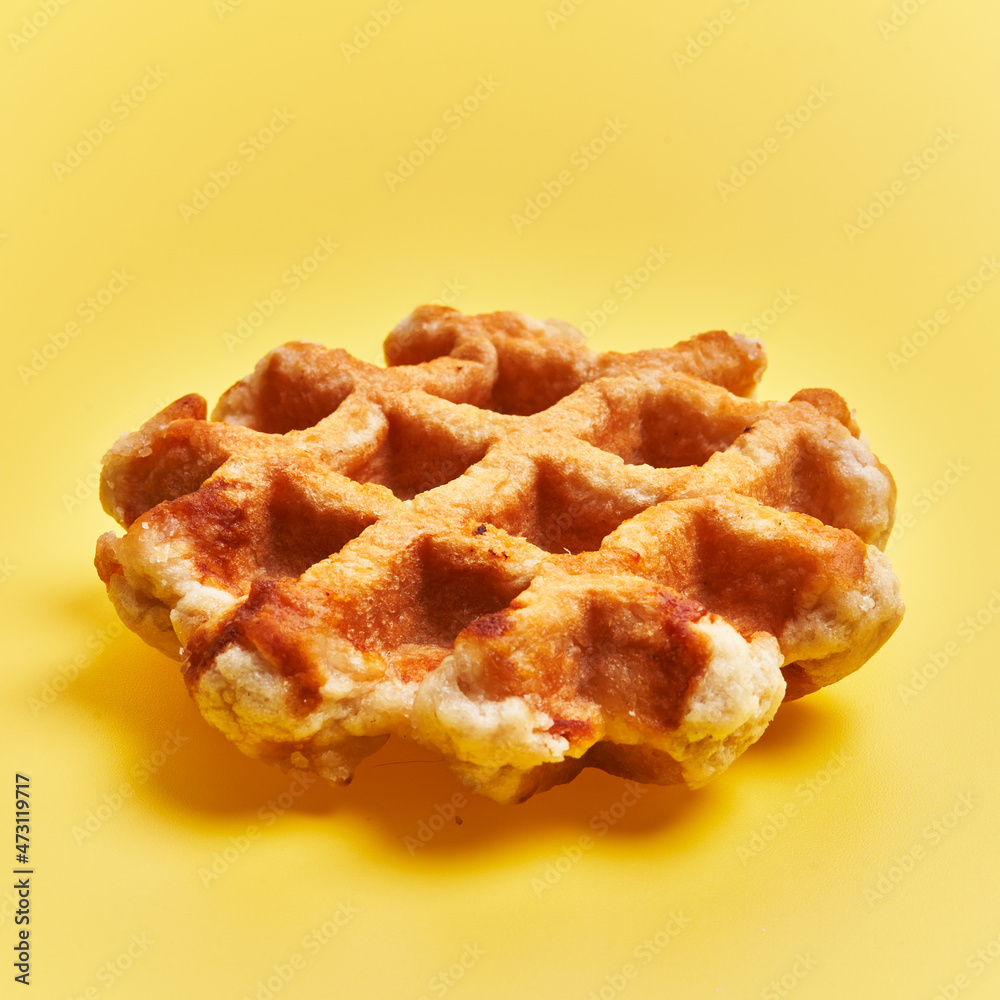 Single delicious waffle over yellow background Single delicious waffle over yellow background