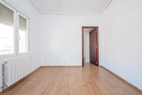 Empty room with chestnut parquet floors and white painted walls