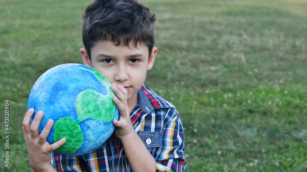 a little boy holds a globe in his hand in a meadow a little boy holds a globe in his hand in a meadow