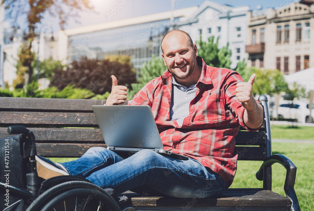 Freelancer with a physical disability in a wheelchair working at the park Freelancer with a physical disability in a wheelchair working at the park