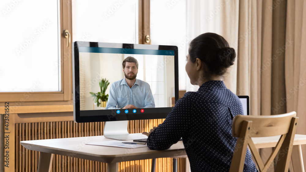 Indian millennial remote employee holding video call, talking to colleague, coach, teacher, working at home office workplace with workstation monitor, display, meeting on boss, negotiating to partner - obrazy, fototapety, plakaty 