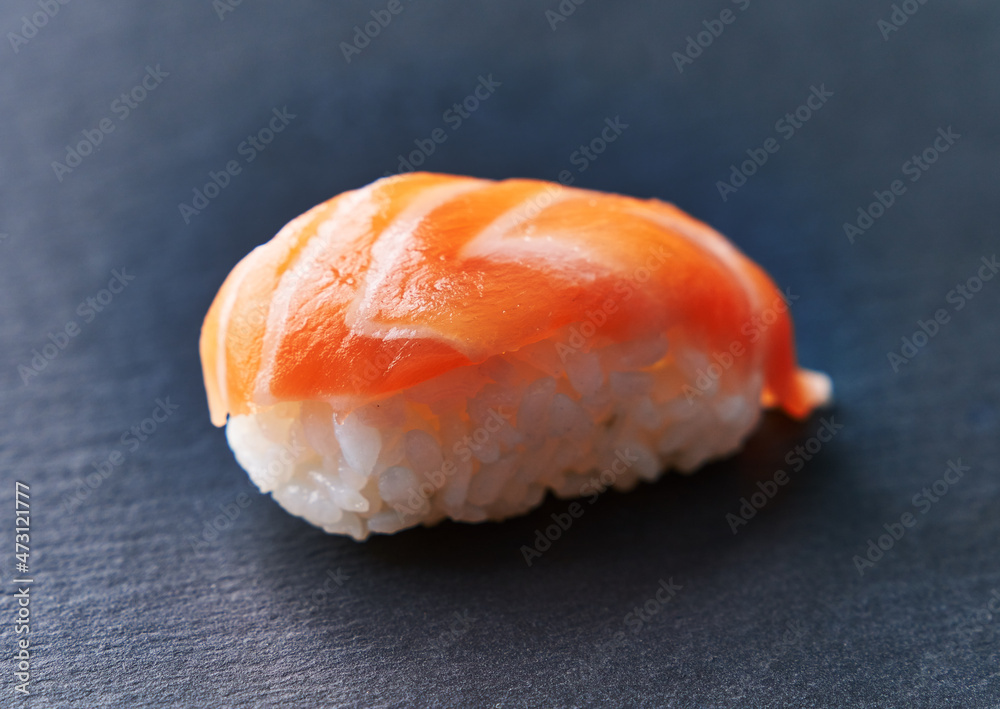  Single salmon nigiri sushi on a blackboard surface