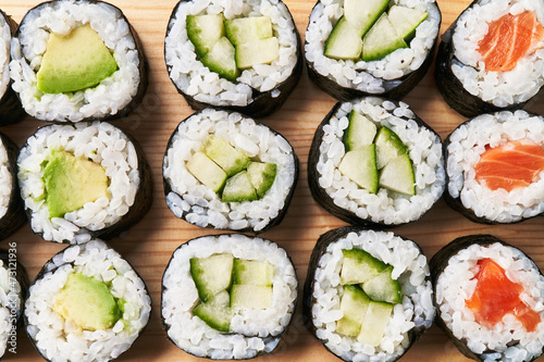  Group of avocado, salmon and cucumber sushi makis on a wooden surface