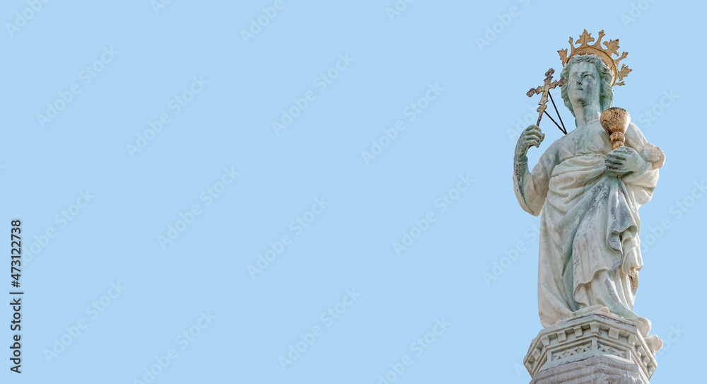 Fototapeta premium Banner with ancient statue of Maria with cross and holy grail at the roof top decoration of Doge Palace in Venice, Italy, at blue sky background with copy space. Concept of architecture heritage sites