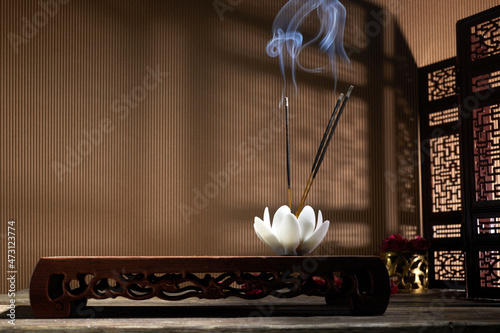 Smoke from burning incense sticks standing on lotus incense holder photo