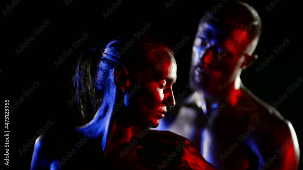 amazing sensual shot of two lovers in darkness, man and woman are covered by shiny golden dye amazing sensual shot of two lovers in darkness, man and woman are covered by shiny golden dye