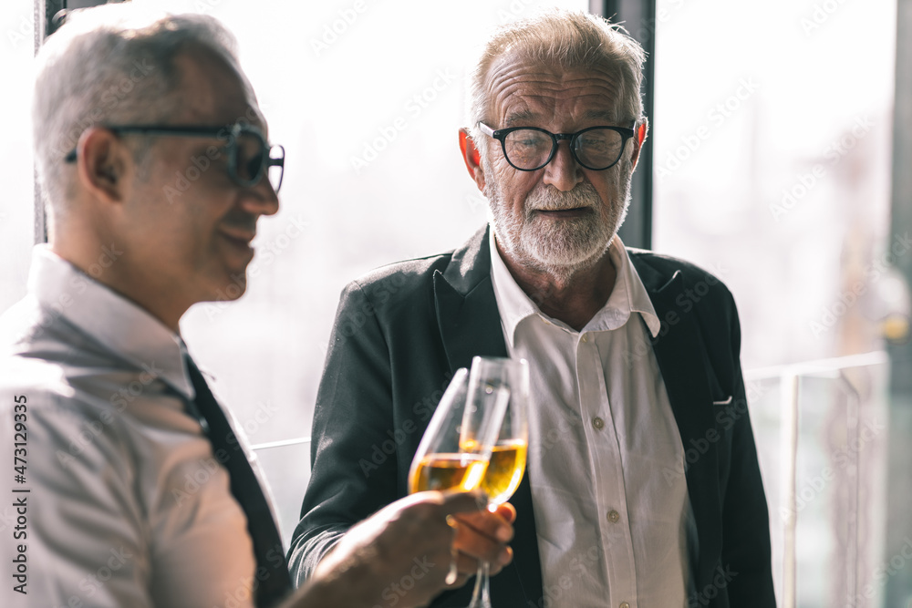 Picture of young business man talking to his older business partner. They are in white shirt and black tie. They are sitting on a table in a hotel lobby. Picture of young business man talking to his older business partner. They are in white shirt and black tie. They are sitting on a table in a hotel lobby.