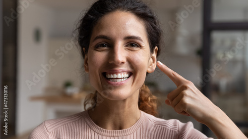 Head shot portrait close up happy woman pointing finger at face  healthy toothy smile and perfect skin  demonstrating result after laser surgery  happy young female excited by vision correction