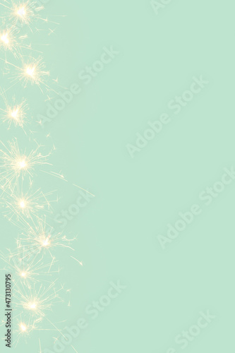 Creative background made of.sprinklers sparks on a mint green backgrund. Minimal New Year concept with copy space.