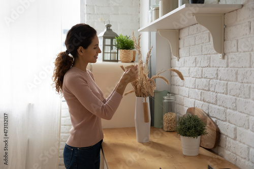 Fotografie Smiling attractive woman homeowner decorating new cozy apartment, first own dwel